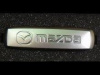 Эмблема Mazda из полированного алюминия для ковриков салона - 1 шт., 18х64 мм